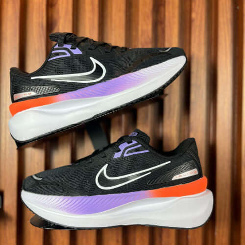 NIKE AIR ZOOM SPEED DAMA black and purple athletic shoes displayed from the side on a wooden background.
